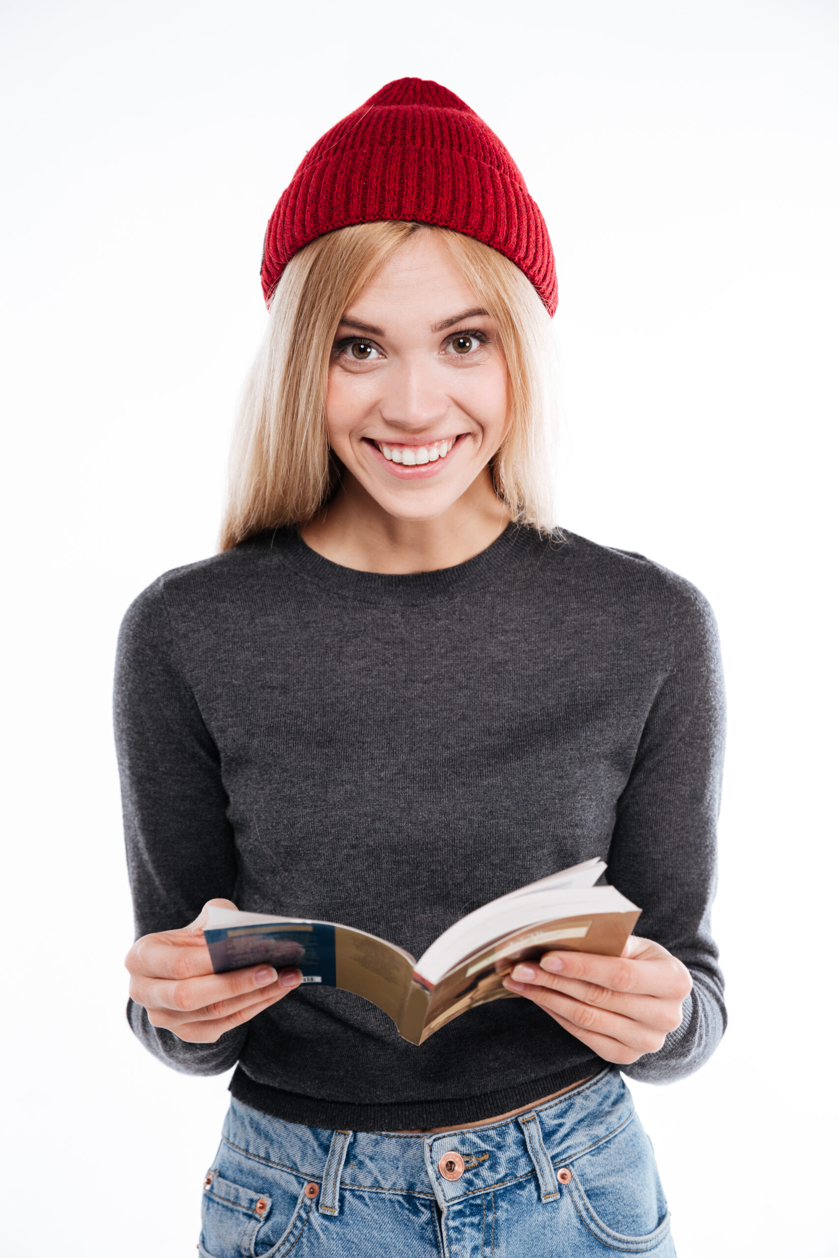 Portrait of a smiling young woman holding open book and looking at camera isolated on the white background